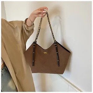 Detailed shot of brown quilted suede tote bag with elegant gold-tone chain and lock hardware