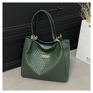 Detail of dark green woven tote bag showing fine leather texture and gold hardware