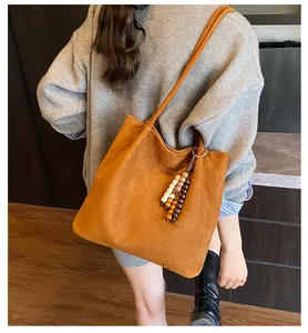 Detail of retro suede shoulder bag with beaded fringe tassel in warm caramel brown