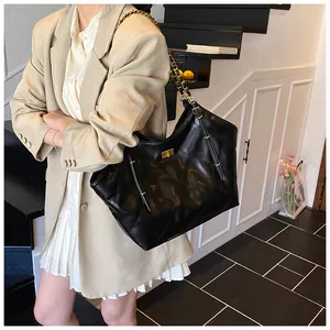 Detail of black quilted tote bag featuring golden twist lock and metal chain strap
