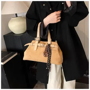 Detail of camel suede tote bag with leather strap buckle and pretzel charm pendant