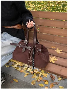 Detail of dark brown vintage suede tote bag with woven knots on a wooden bench