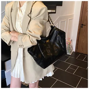 Detailed view of black quilted leather tote bag with gold chain strap on model