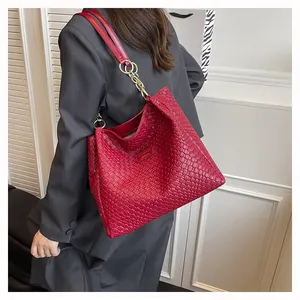 Close-up of a red woven leather tote bag with elegant gold chain shoulder strap details