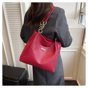 Detail of red woven tote bag with large gold chain strap and high-quality leather texture