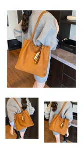 Detail of a brown suede tote bag featuring a decorative multi-colored wooden bead tassel