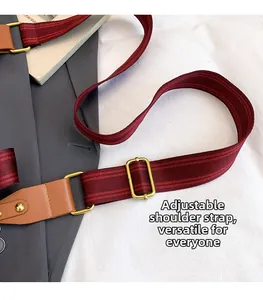 Detail eines verstellbaren tiefroten Streifenriemens mit braunem Leder und Bronzeschnallen