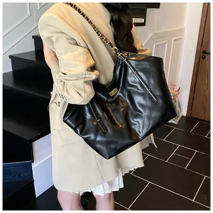 Detail of classic diamond-quilted pattern and gold chain strap on black tote bag