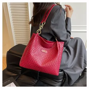 Close-up of red woven tote bag featuring gold chain hardware and fashion brand plaque