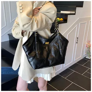 Classic black quilted tote bag with golden chain strap worn by a model in a modern setting