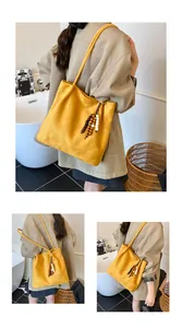 Close-up of a yellow suede tote bag featuring retro wooden bead tassel decorations