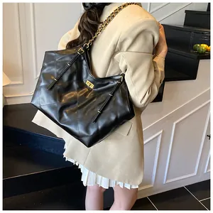 Detail of the black quilted tote bag showing gold twist-lock and chain shoulder strap