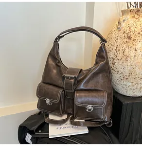 Detailed view of dark brown vintage leather shoulder bag with white contrast stitching