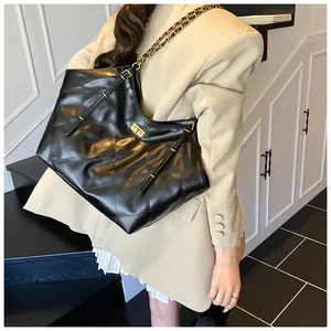 Close-up of black quilted leather tote bag with gold twist lock and woven chain strap