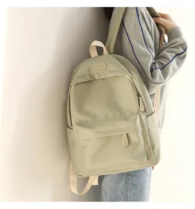 Close-up of a light green waterproof oxford backpack featuring cream-white straps and front pocket