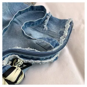 Détail d'un sac cabas en jean délavé avec fermeture éclair bleue et bords effilochés