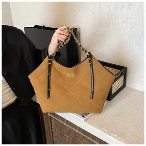 Detail of brown quilted suede tote bag with golden twist lock and chain strap
