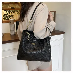 Detail of woven leather tote bag with gold chain straps and spacious interior design