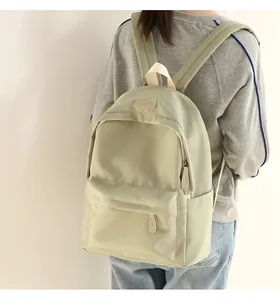Rear view of a light green waterproof Oxford backpack being worn on a simple background