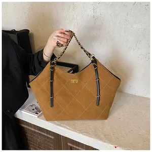 Detail of brown quilted suede tote bag featuring a gold square twist lock and chain strap