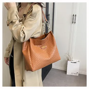 Detailed view of brown woven tote bag with chain strap and elegant texture on shoulder