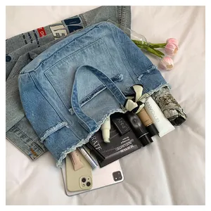 Détail de l'intérieur du grand sac cabas en jean montrant les objets et bords effilochés