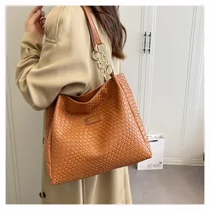 Detail of caramel braided leather texture and gold chain strap on large tote bag
