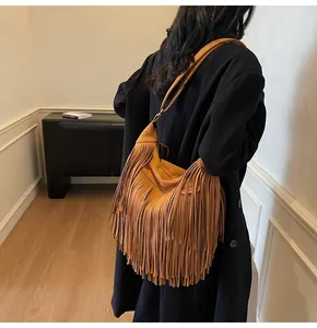 Rear view of model wearing a brown fringe hobo bag with bohemian suede details