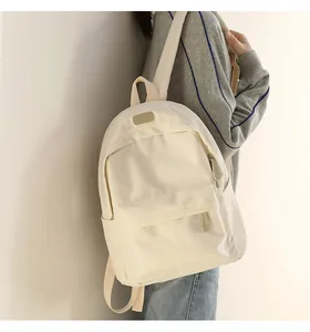 Detail shot of the front zipper pocket and AHIAMBAG brand label on the beige backpack