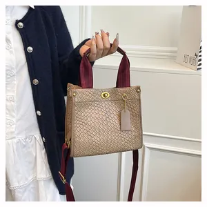 Detail der beige geflochtene Tragetasche mit burgunderroten Trägern und Gold-Drehverschluss