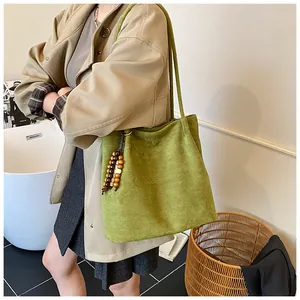 Detail of green suede tote bag featuring retro wooden bead tassel and long shoulder strap