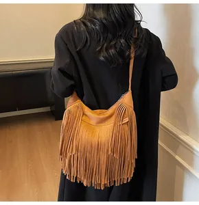 Detail of a brown suede crossbody bag featuring long tassels and a half-moon shape design