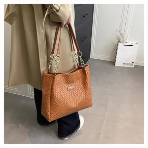 Detail of a brown woven tote bag with metallic rings shown in a lifestyle commuter scene