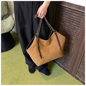 Detail of a brown quilted suede tote bag with a gold chain handle and twist lock closure