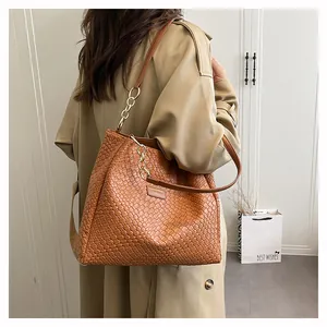 Detail of woven texture and chain strap on a caramel brown large capacity tote bag