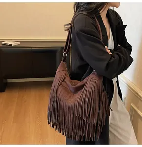 Detail of dark brown suede shoulder bag with long fringes and bohemian vintage style