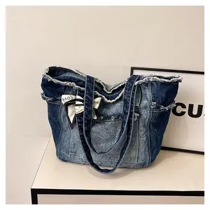 Détail du sac cabas en jean vintage avec bords effilochés et foulard en soie décoratif