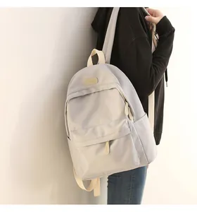 Back view of a light grey waterproof oxford backpack worn by a model in minimalist setting