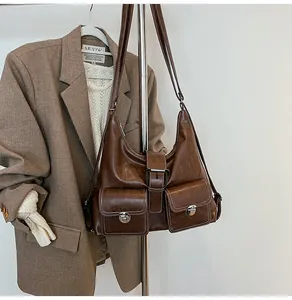 Detail of dark brown vintage leather shoulder bag featuring dual front pockets and metal buckles