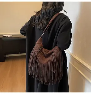 Close-up of deep brown suede brown fringe hobo bag worn with black wool coat for women