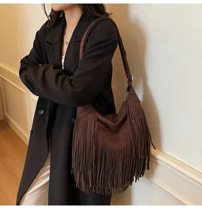 Detail of dark brown suede crossbody bag featuring long fringe tassels and hobo silhouette