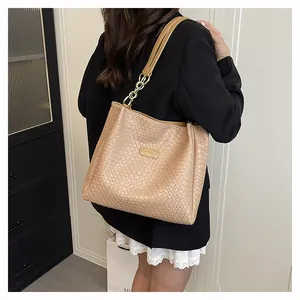 Detail of woven faux leather texture and golden metal logo plate on beige tote bag