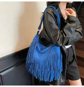 Detail of vibrant blue fringed crossbody bag featuring premium matte suede texture