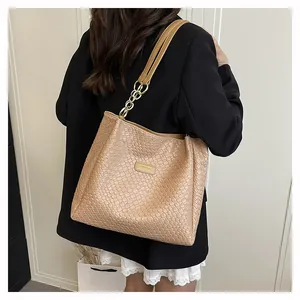 Detail of woven texture beige tote bag featuring elegant golden metal chain shoulder strap