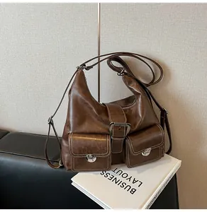Detail of vintage caramel brown crossbody bag featuring dual front pockets and silver buckles