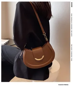 Dettaglio della borsa a sella marrone con fibbia dorata su un outfit blazer nero