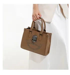 Detail view of brown punk tote bag with silver skull ornament and metallic studs