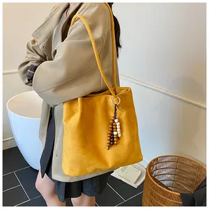 Detail of ginger suede tote bag with colorful wooden bead pendant and slim shoulder strap