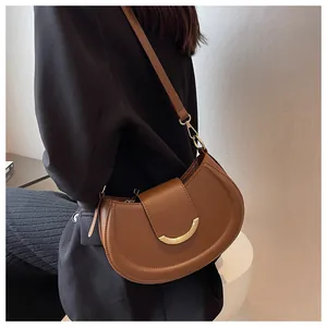 Detail view of a brown crescent moon shoulder bag with gold metal buckle on a model