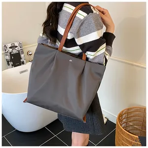 Grote geplooide shopper met bruine leren riemen en een metalen drukknoopsluiting